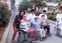 大连市爱心养老院护理人员和老人在园里散布